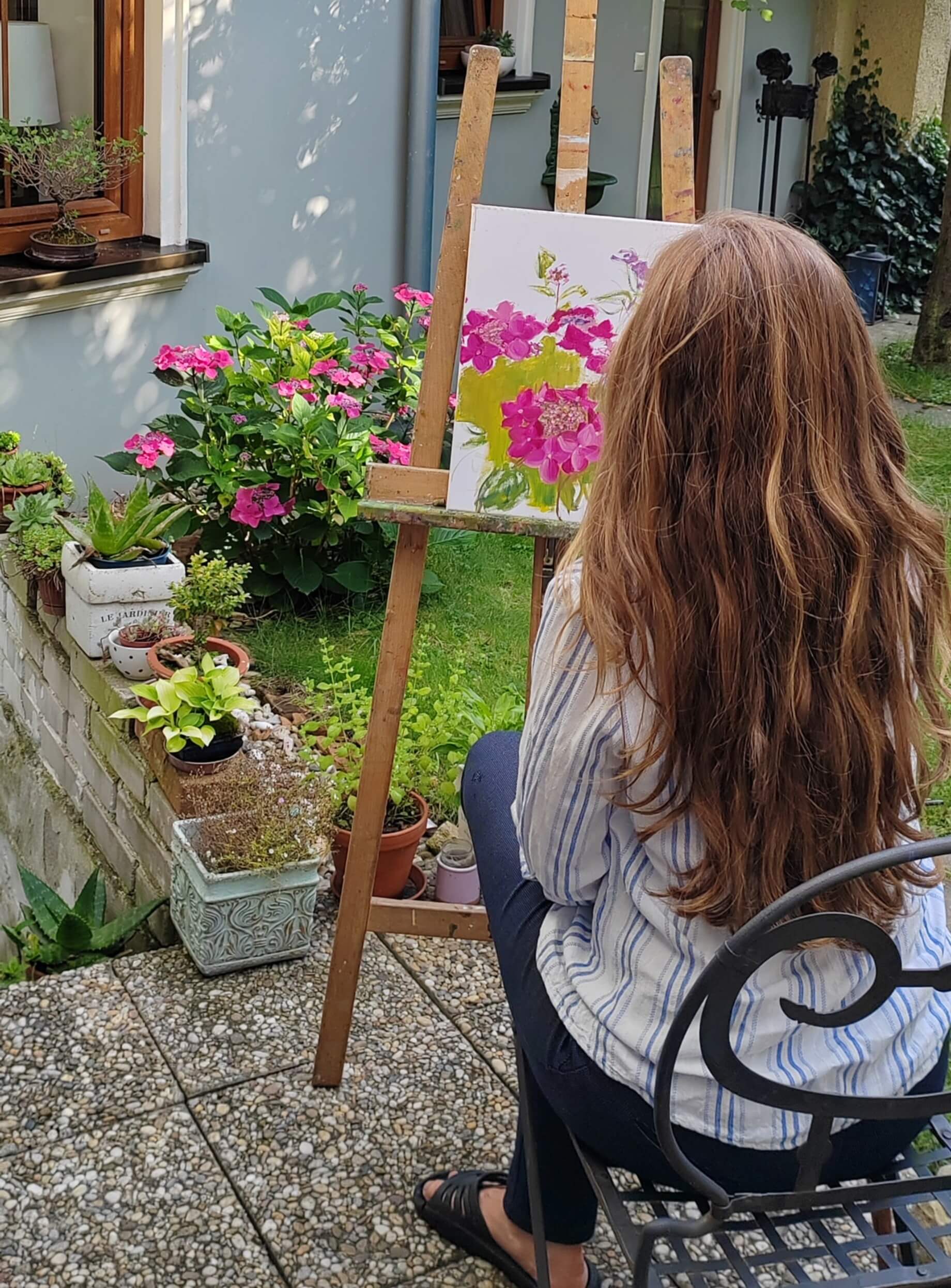 Detail umělecké práce - Jana Bayerová maluje květiny štětcem na plátno